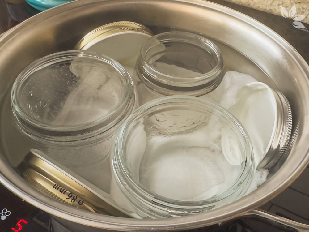 Potes de vidro em panela com água fervente para esterilização caseira de geleias.